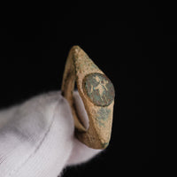 Roman bronze ring Verecundus held in a gloved hand, oblique view of the engraved disc bezel