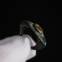 Roman bronze ring Vultinus held in a gloved hand, angled view of bezel and flared shoulders