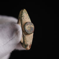 Roman bronze ring 'Tullia' held in a gloved hand, showing the worn and illegible bezel device