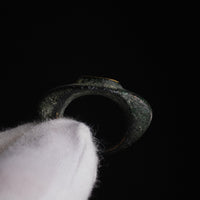 Roman bronze ring Vultinus held in a gloved hand, side view of the hoop and raised bezel