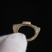 Roman bronze ring 'Tullia' held in a gloved hand, showing the hoop, flared shoulders and raised bezel