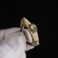 Angled view of Roman bronze ring 'Tullia' in a gloved hand, showing the sandy patina and disc bezel