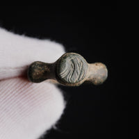 Roman bronze signet ring Corvidus held in a gloved hand, bezel with the engraved bird facing the viewer