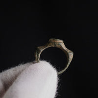 Roman bronze signet ring Corvidus on a gloved fingertip, profile showing the hoop opening and bezel edge