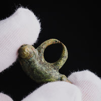 Suspension loop and terminal knob of Roman bronze phallic amulet 'Felix' in a gloved hand