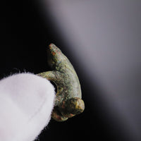 Side view of Roman bronze phallic amulet 'Felix' held between gloved fingers