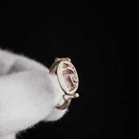 Roman silver ring Numeria held on a gloved finger, close-up of the intaglio draped figure