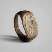 Roman silver ring Tychion with raised oval bezel showing a standing figure in low relief, three-quarter view.