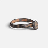 Byzantine bronze ring 'Georgios' shows its engraved circular bezel and narrow shoulder at an angle.