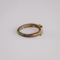 Side profile of medieval bronze ring Cruciata revealing D-section hoop and patina