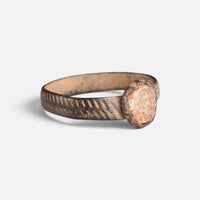 Medieval bronze ring 'Luminara' shows its pale setting and diagonal band decoration at an angle.