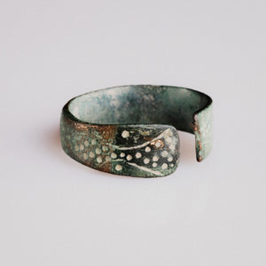 Side view of medieval bronze ring Vesna showing incised wave-scroll and dot clusters on terminal