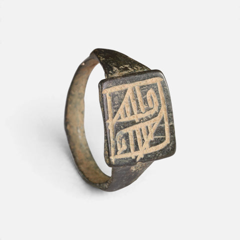 Medieval Islamic bronze ring 'Rashida' shows its rectangular bezel engraving and complete hoop at an angle.