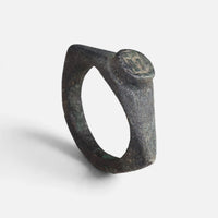Roman bronze ring 'Hesperia' shows its worn circular bezel and complete angular hoop at an angle.