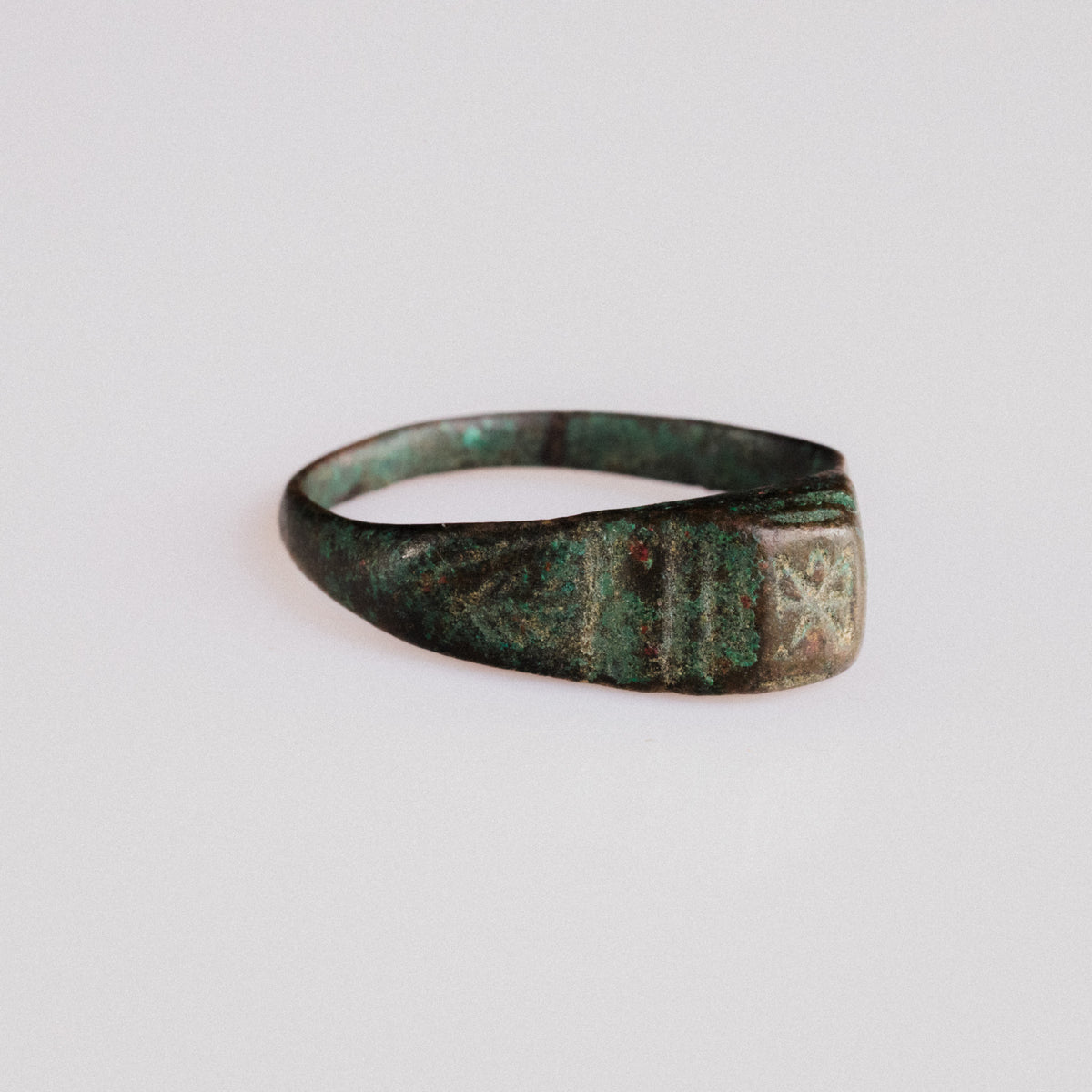 Side view of Roman bronze ring Numerius showing grooved shoulders and green patina
