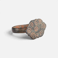 Medieval bronze ring 'Radvina' shows its decorated lobed bezel and hoop at an angle.