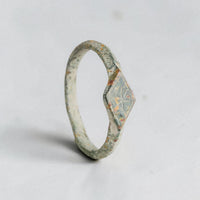 Three-quarter view of medieval bronze signet ring Stellira with legible incised star on diamond bezel