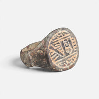 Medieval Islamic bronze ring 'Tahir' shows its engraved round bezel and broad shoulder at an angle.