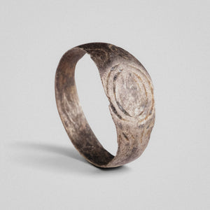 Silver band ring 'Ovata' shows its concentric oval engraving above its complete hoop at an angle.