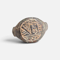 Medieval Islamic bronze ring 'Tahir' shows angular engraved strokes within the round bezel border from the front.