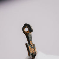 Top view of medieval bronze cross pendant 'Okellaris' showing the pierced suspension loop