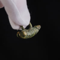 Underside detail of Roman bronze fascinum pendant 'Felix' held in a gloved hand